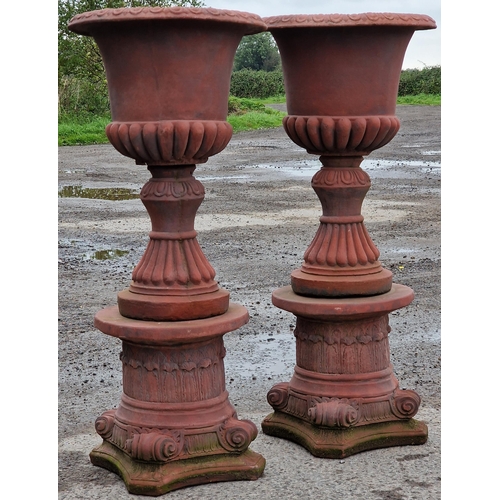 1062 - Pair of reconstituted stone garden urns with lobed bowls and flared rims, raised on Corinthian colum... 