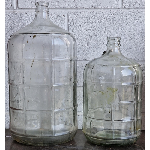 1111 - Two large glass bottles with ribbed detail, the largest 55cm high, the other 42cm high (2)