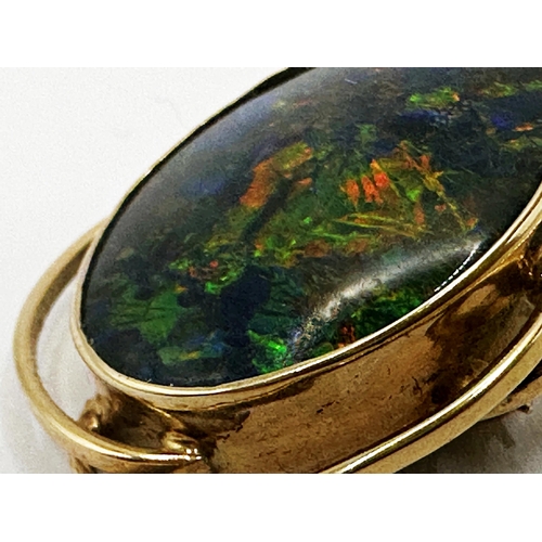 179 - Mid 20th century yellow metal black opal brooch in scrolled mount, the stone 20 x 15mm, 3cm high in ... 