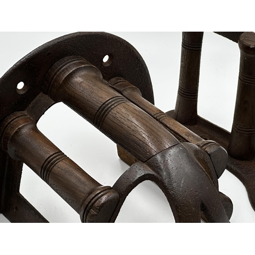 606 - Two antique cast iron and turned wooden saddle racks by Musgrave, the largest 33cm long (2)