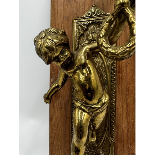 322 - Cast brass figural sconce, modelled as a cherub, upon a fruitwood plaque, 41cm high