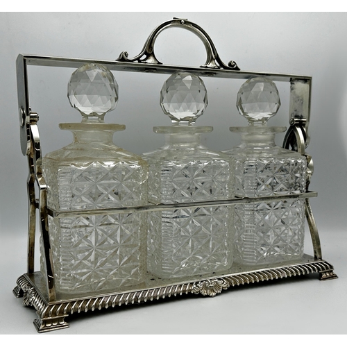 1243 - Good quality silver plated three bottled tantalus comprising three square cut glass bottles within a... 