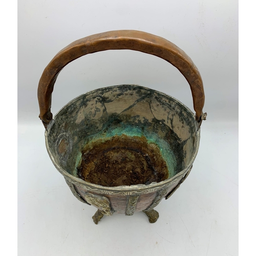 2384 - Copper and brass four footed Moroccan bowl with handle. H 38cm.