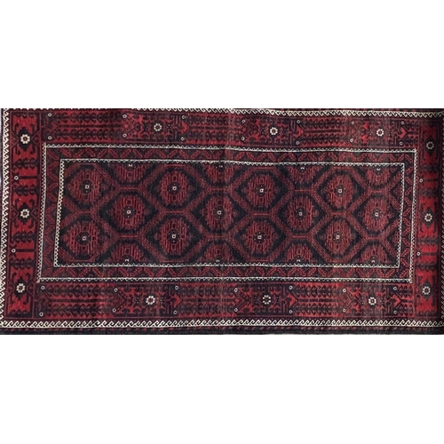 1430 - Persian Meshad Belouch rug with geometric red decoration on black ground, 220 x 115cm