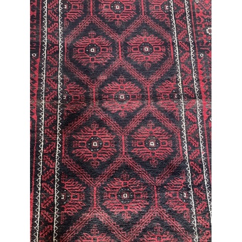 1430 - Persian Meshad Belouch rug with geometric red decoration on black ground, 220 x 115cm