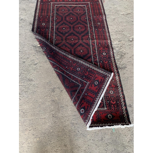 1430 - Persian Meshad Belouch rug with geometric red decoration on black ground, 220 x 115cm