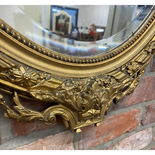 1057 - Late 19th century continental gilt wood and gesso oval wall mirror, mounted by plaster work wreath a... 