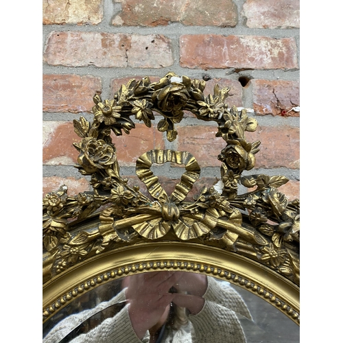 1057 - Late 19th century continental gilt wood and gesso oval wall mirror, mounted by plaster work wreath a... 