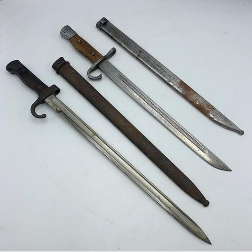 2414 - Two hooked quillion bayonets with fullered blades, metal scabbards and wooden grips, makers marks st... 