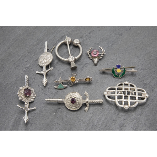 110 - A collection of eight Scottish white metal pieces to include kilt pin, three broad sword brooches et... 