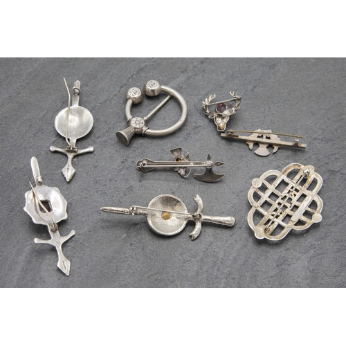 110 - A collection of eight Scottish white metal pieces to include kilt pin, three broad sword brooches et... 