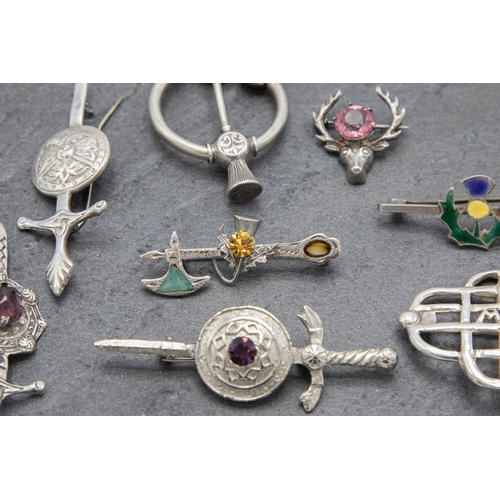 110 - A collection of eight Scottish white metal pieces to include kilt pin, three broad sword brooches et... 