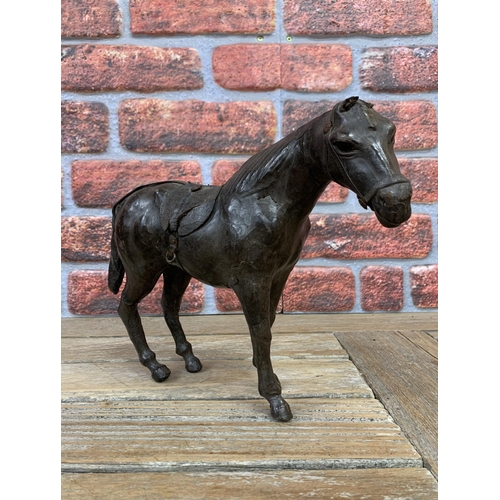 336 - 19th century leather clad horse figure with saddle and glass inset eyes, H 23cm x L 31cm