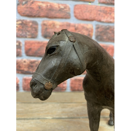 336 - 19th century leather clad horse figure with saddle and glass inset eyes, H 23cm x L 31cm