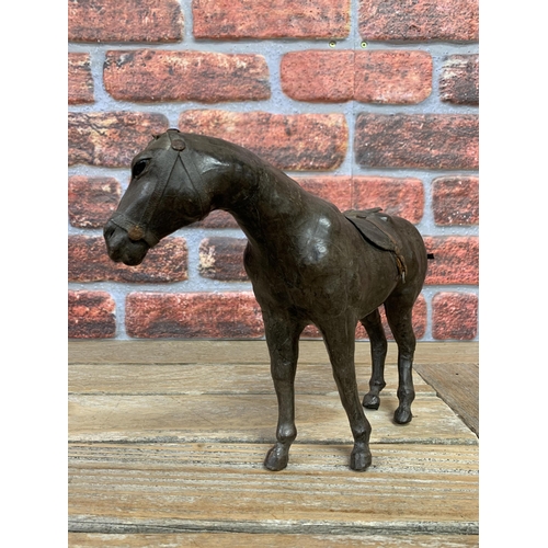 336 - 19th century leather clad horse figure with saddle and glass inset eyes, H 23cm x L 31cm