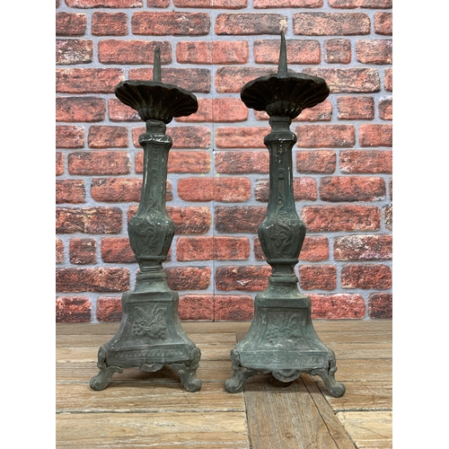 2231 - Pair of antique patinated sheet metal pricket sticks on embossed tri form columns, 63cm high (2)