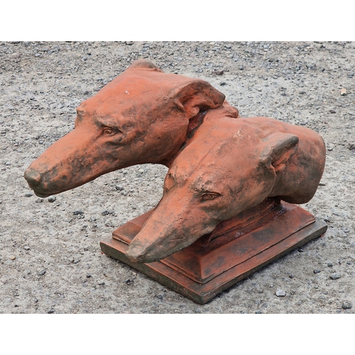 1010 - Composite terracotta study of two greyhound heads upon a stepped square base, 46cm long