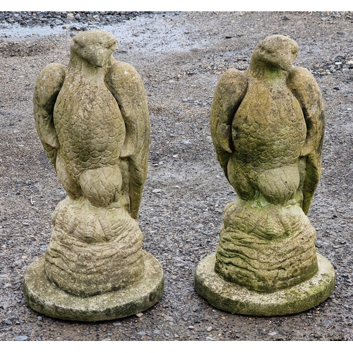 1054 - Pair of weathered reconstituted stone garden statues in the form of eagles, H 45cm