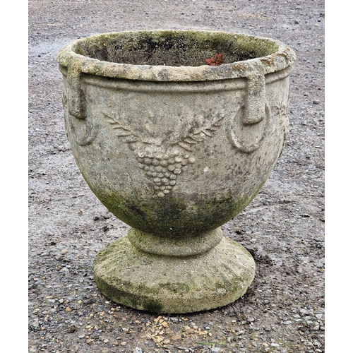 1057 - A weathered reconstituted stone garden urn with grape and ring relief, H 50cm x W 45cm