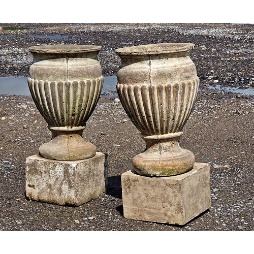 1064 - A pair of reconstituted stone urns with lobed bowls raised on square cut plinths, H 55cm x W 25cm