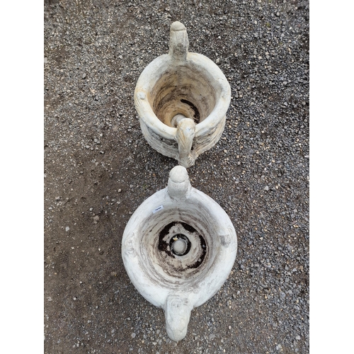 1086 - A pair of reconstituted stone two sectional trophy shaped garden urns with scrolled foliate relief d... 