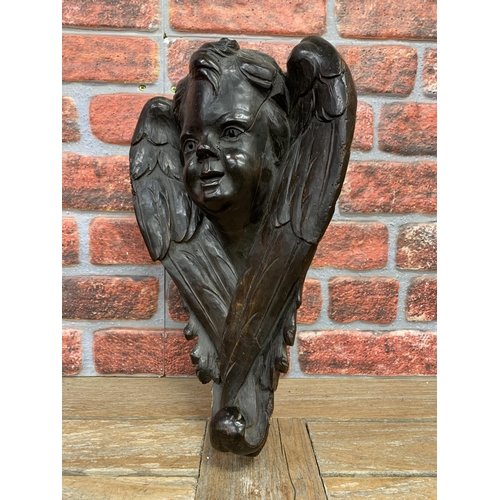 2175 - 19th century stained softwood cherub bracket, the well carved face flanked by crossed opposing wings... 