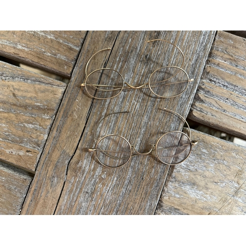 155 - Two pairs of antique yellow metal spectacles (displayed in cabinet)