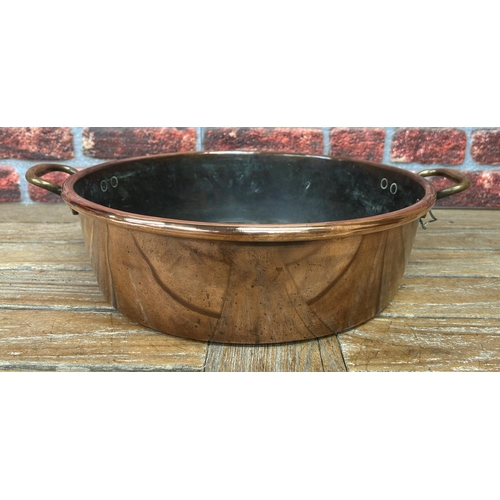 491 - Large antique polished copper twin handled cooking pot with further smaller example, largest D 44cm ... 