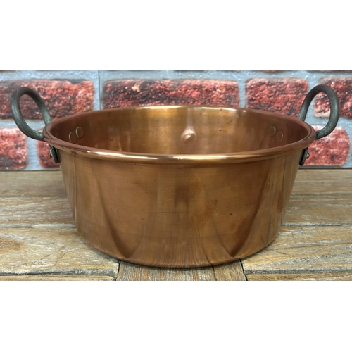 491 - Large antique polished copper twin handled cooking pot with further smaller example, largest D 44cm ... 