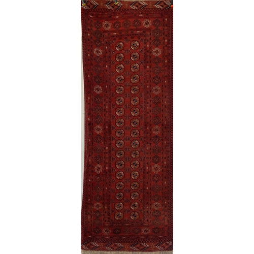 1606 - Bokhara runner, typical geometric medallions on a red ground, 300 x 105cm