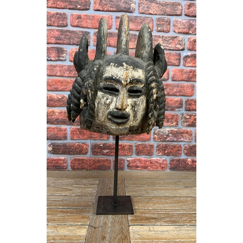 392 - Nigerian Igbo tribal double faced mask, caolin and pigment decoration, atop metal stand, H 68cm