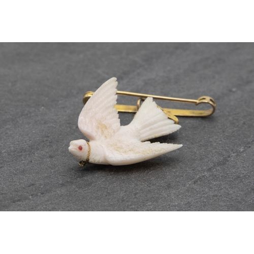 138 - Unusual 9ct bar brooch with carved white coral dove with gem set eye, 6cm high in total