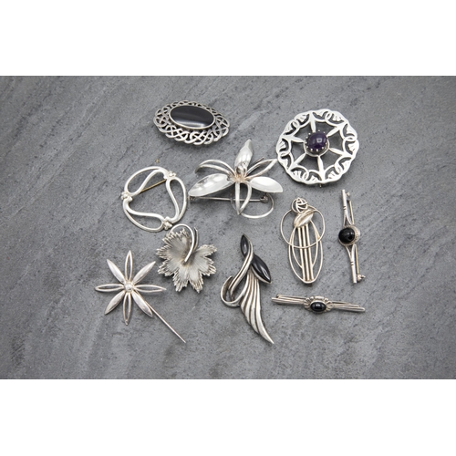 144 - Ten silver brooches to include Scottish examples, 73.6g, within Morocco leather case