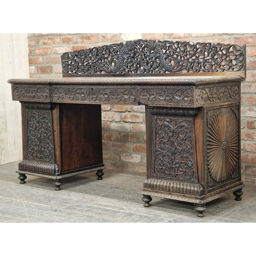 1291 - Anglo Indian profusely carved hard wood pedestal desk with gallery back, raised on turned supports, ... 