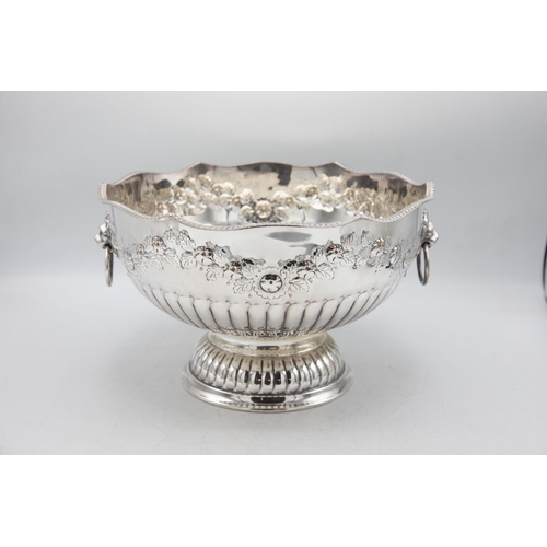 156 - Large silver plate punch bowl with lion head handles and repoussé foliage, raised atop circular foot... 