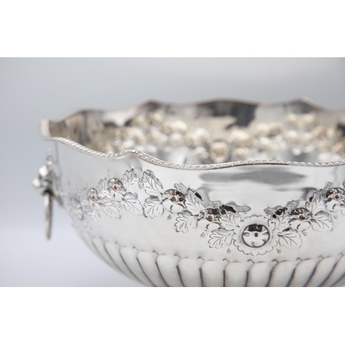 156 - Large silver plate punch bowl with lion head handles and repoussé foliage, raised atop circular foot... 