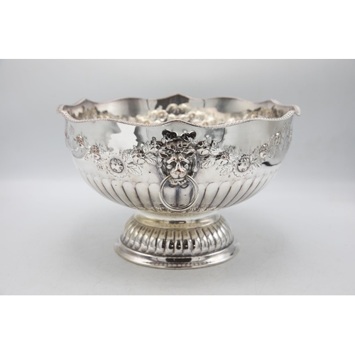 156 - Large silver plate punch bowl with lion head handles and repoussé foliage, raised atop circular foot... 