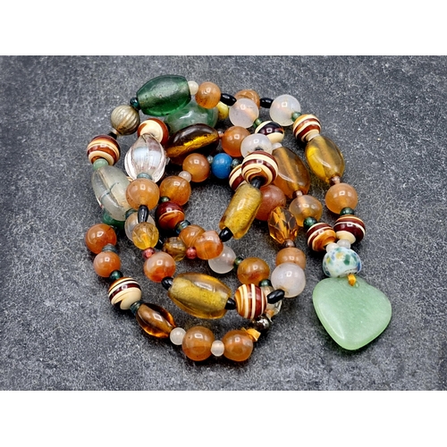 129 - Carved jade bead necklace, hand knotted, 55cm long with a further jade and amber type bead necklace ... 