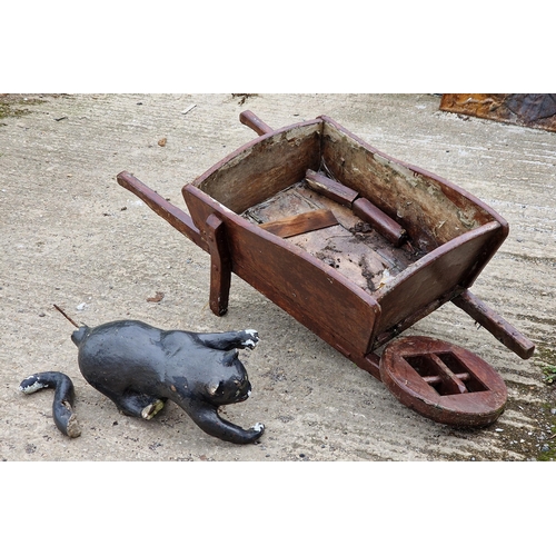 1054 - Painted reconstituted stone cat garden ornament, together with a vintage wheelbarrow (AF) (2)