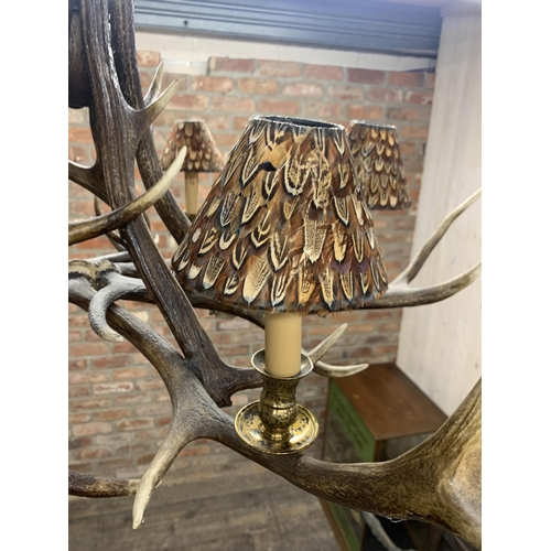 1402 - Impressive stag antler six light chandelier, each shade having pheasant feather decoration, D 110cm ... 