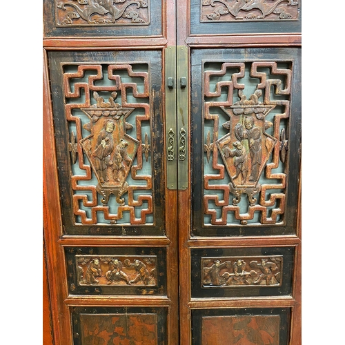 1234 - Chinese red laquered cabinet, twin doors pierced and carved with figures, enclosing shelves, two dra... 