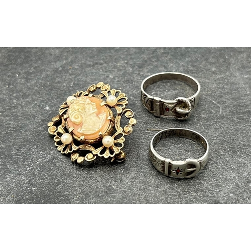 56 - Two silver buckle rings, with inset red gem, Size R and L respectively, with a silver gilt and pearl... 