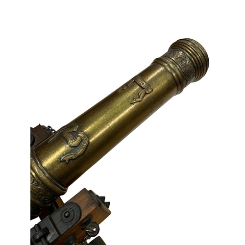 222 - Two brass desktop cannons atop carved wooden carriages, each having the breech of the cannon tube ad... 