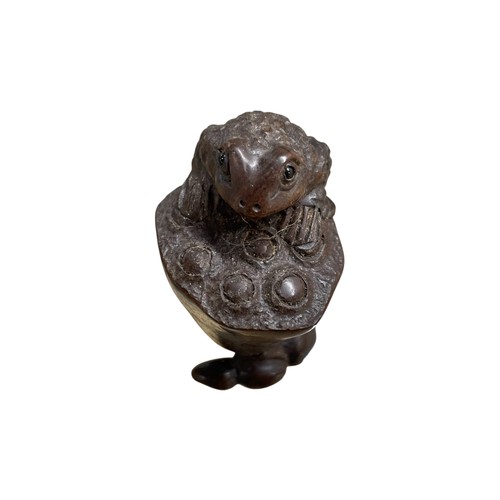 274 - Japanese carved netsuke in the form of a frog climbing a lotus bud, glass eyes and inset tablet sign... 