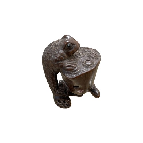 274 - Japanese carved netsuke in the form of a frog climbing a lotus bud, glass eyes and inset tablet sign... 