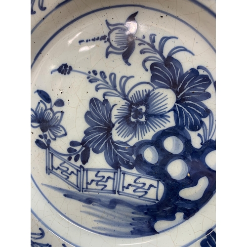 356 - English Delft blue and white plate decorated with a Chinese garden arrangement of flowers, D 22.5cm