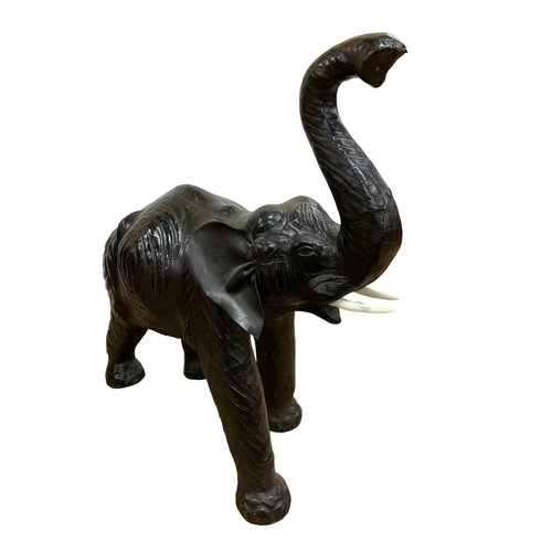 1465 - Pair of black leather elephant sculptures, in the manner of Liberty, each having original faux ivory... 