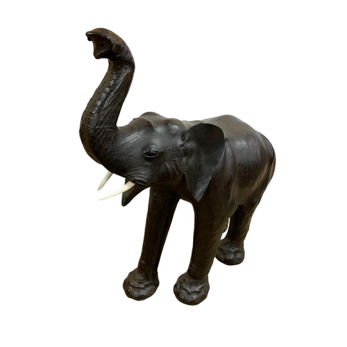 1465 - Pair of black leather elephant sculptures, in the manner of Liberty, each having original faux ivory... 