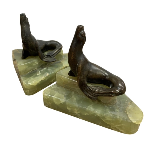 180 - Pair of Art Deco onyx bookends addorned with bronze sealion decoration, H 9cm x W 10cm x D 9cm