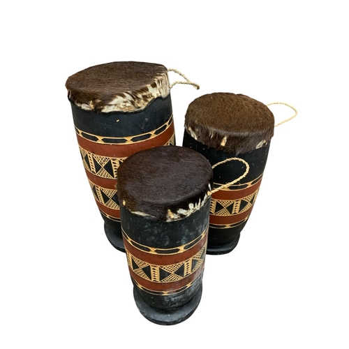 296 - Three African tribal hand carved wood and animal hide topped graduating drums, largest H 45cm